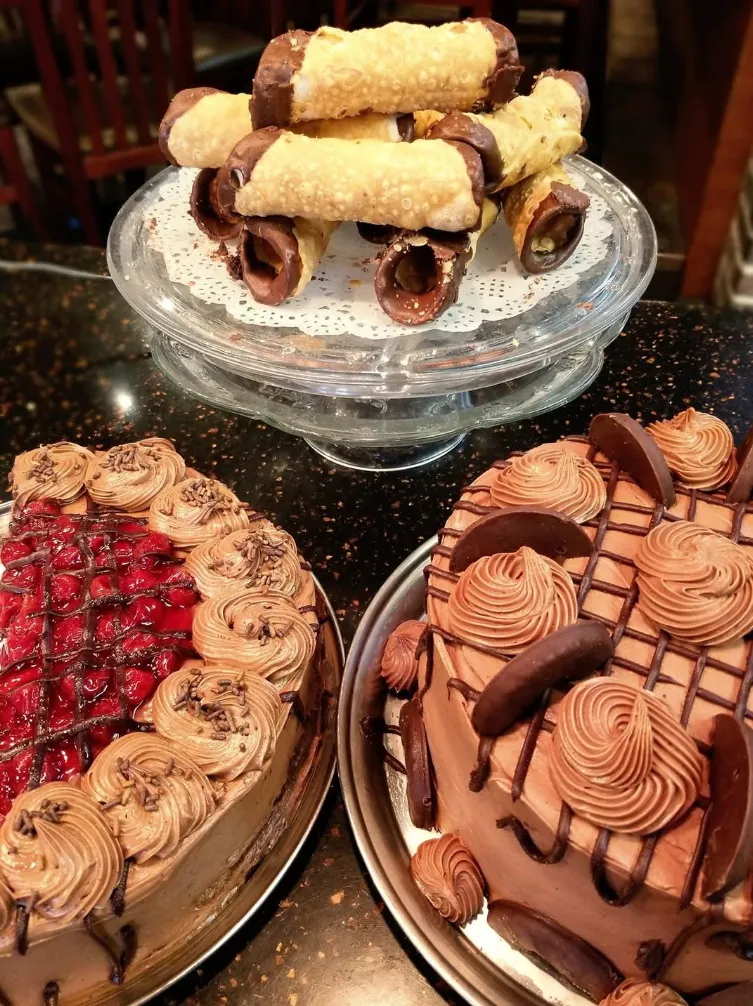 Layer cakes on stands in front of the Christo’s neon sign