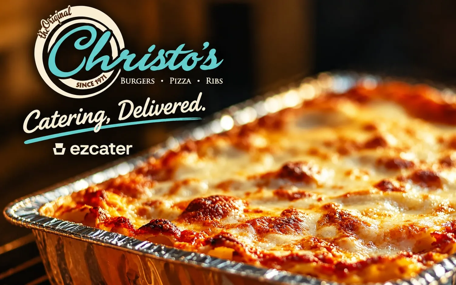 Catering, delivered through ezCater: a bubbling pan of lasagna fresh out of the oven under the Christo's logo